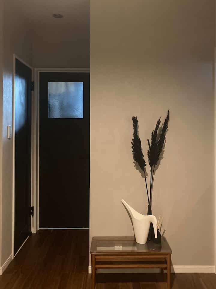 Natural and wood tone entrance featuring a simple side table with a white watering can, creating a calm atmosphere