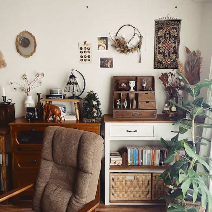 ブラウンとホワイトのナチュラルなリビング、ヴィンテージの小物や本棚、ゆったりした椅子が配置された雰囲気のあるインテリア