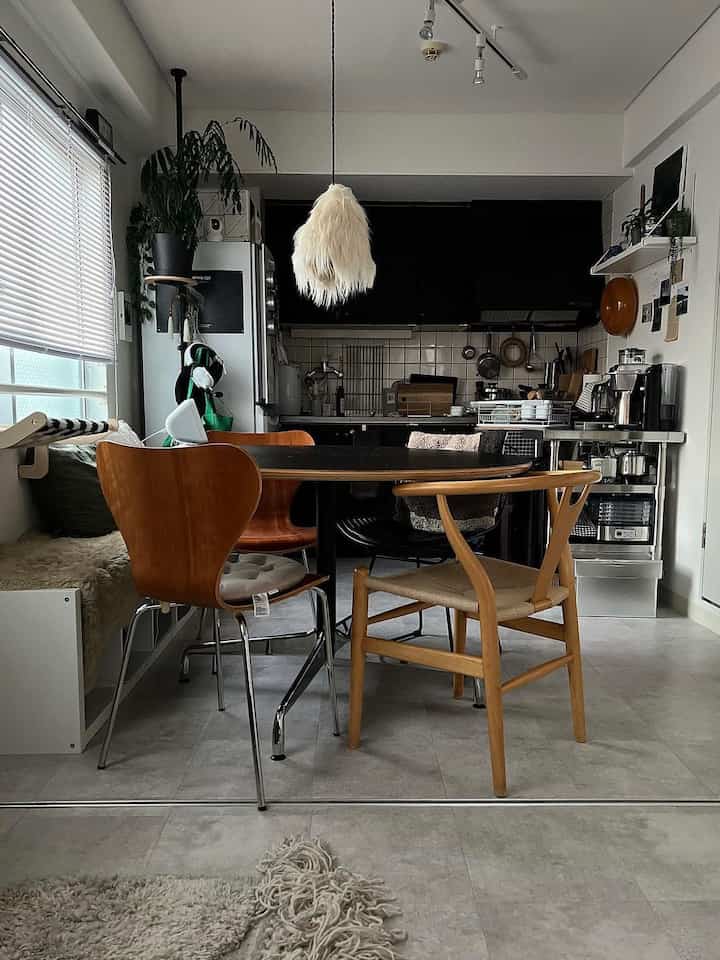 Black and wood-toned kitchen and dining room with natural light and plants creating a cozy atmosphere