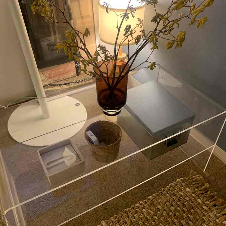 ナチュラルカラーの床と透明なテーブルの上に茶色の花瓶と照明が置かれた、雰囲気のある小さな部屋のインテリア