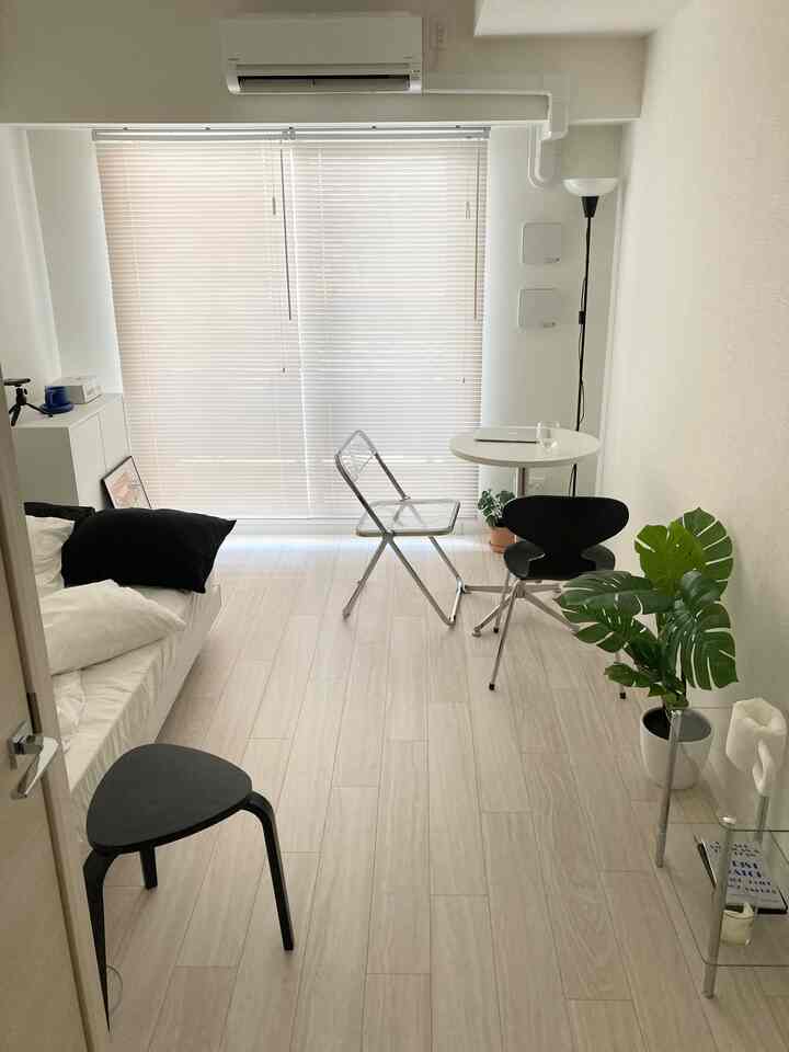 Small bedroom space in white and black tones, featuring a sofa bed and round table arranged with simple balance