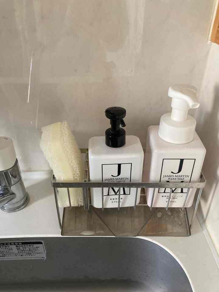 白とステンレスを基調としたコンパクトなキッチンシンク、スポンジホルダーと洗剤ポンプが整頓された収納スペース