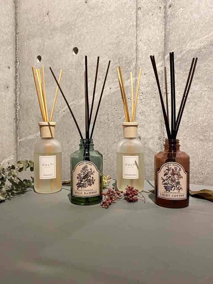 Modern entrance setting with four diffusers arranged against a natural tone concrete wall, showcasing fragrance items