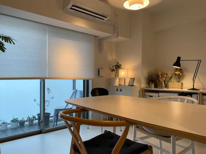 Cozy dining room with bright white and wood tones, featuring a simple dining table and blinds in a minimalistic interior space