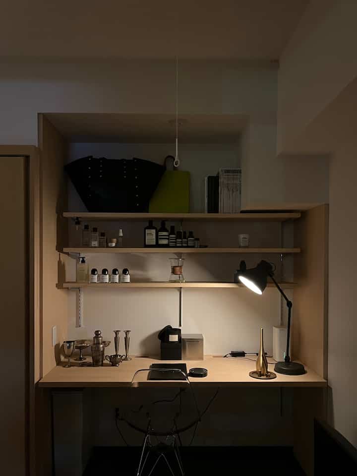 ブラウンの木目調の棚とデスク、ブラックのテーブルランプが配置された整ったホームオフィスの空間