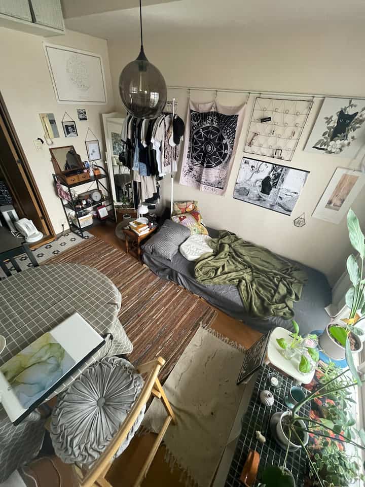 Natural tone compact studio bedroom with framed wall art and pendant lighting creating a cozy atmosphere