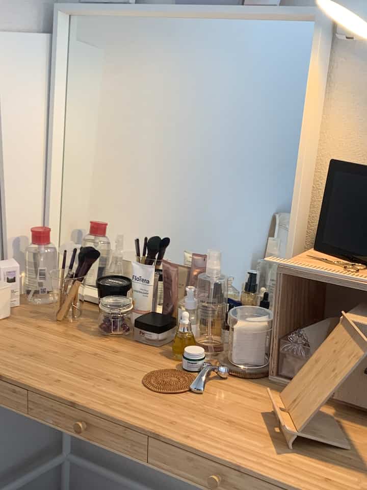 ナチュラルカラーの化粧台、透明なアクリル収納と多様なメイク道具が整然と配置された雰囲気のあるインテリア