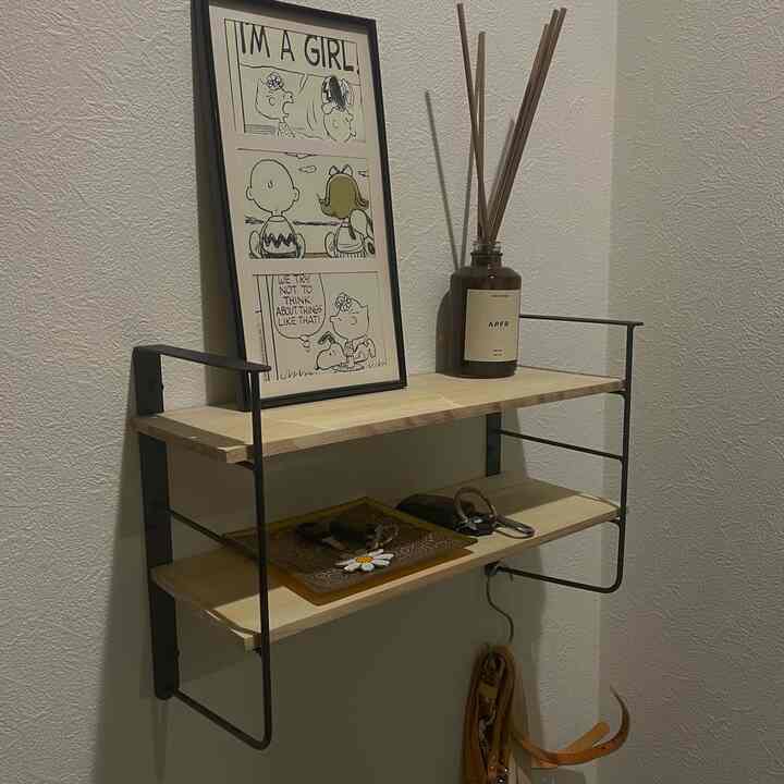 Natural color and wood tone entrance space featuring wall-mounted shelves with picture frame and diffuser on a clean storage setup