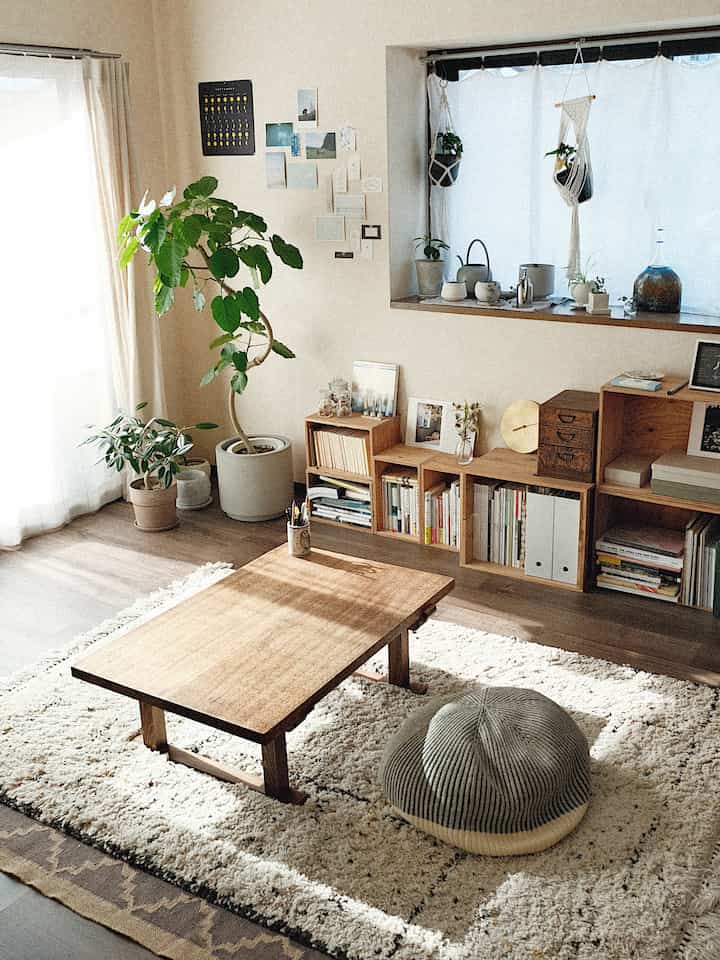 Natural-toned living room with warm wood tones featuring a low wooden table, cushion, and plants creating a cozy atmosphere