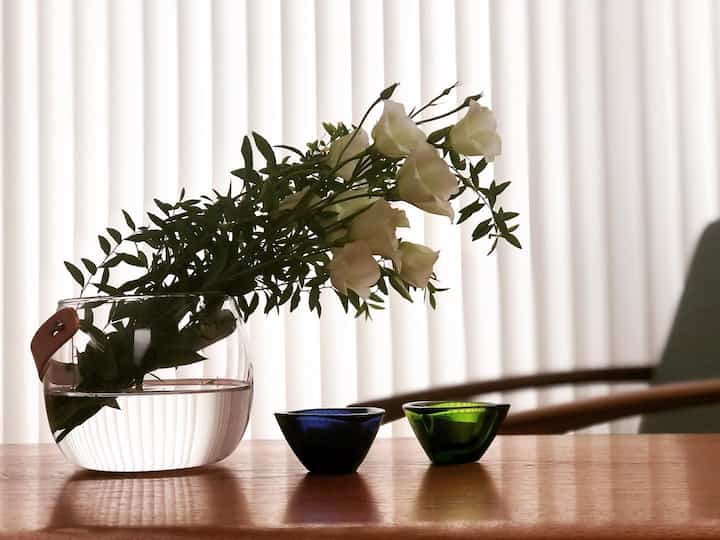 ナチュラルカラーの木製テーブルに透明な花瓶と白い花が置かれたスカンジナビアスタイルのインテリア