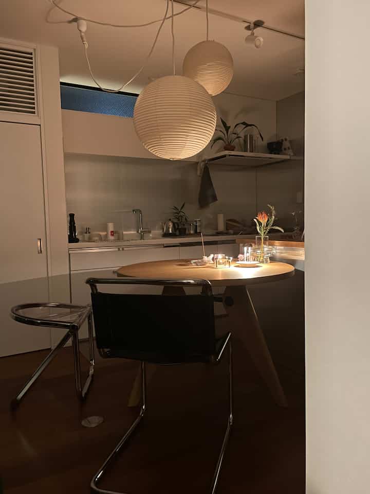 Wood-toned and transparent chair modern dining room featuring pendant lights and candles creating a cozy night ambiance