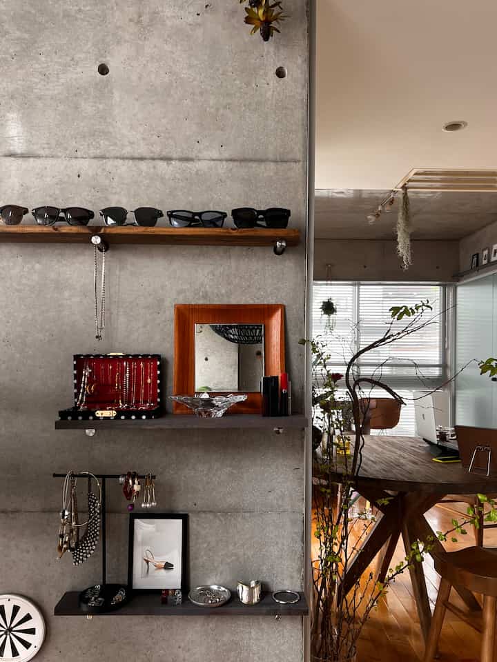 Natural toned living room corner with concrete wall, wooden furniture, and organized accessories.