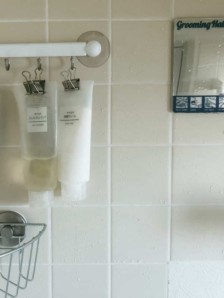 白いタイルの壁と収納アイデアがあるバスルーム、清潔で衛生的な雰囲気のインテリア