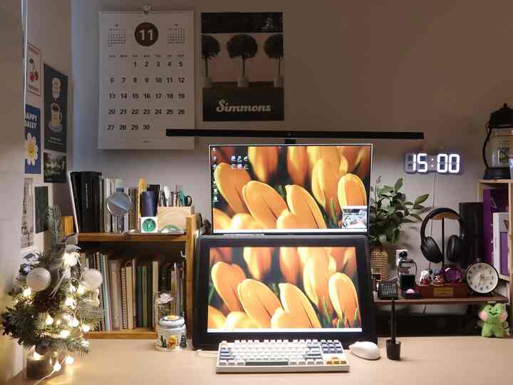 Wood tone and white-walled home office desk space featuring dual monitors and Christmas decorations, creating a cozy holiday atmosphere