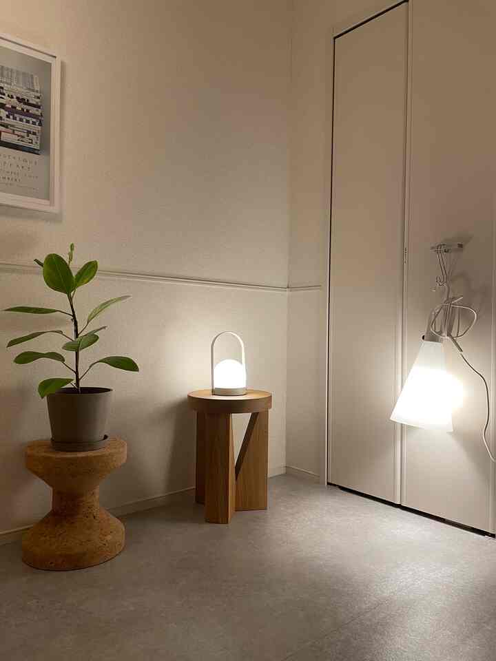 ナチュラルな色調の小さな空間、木製のテーブルにテーブルランプと植物が配置されたシンプルな雰囲気のインテリア