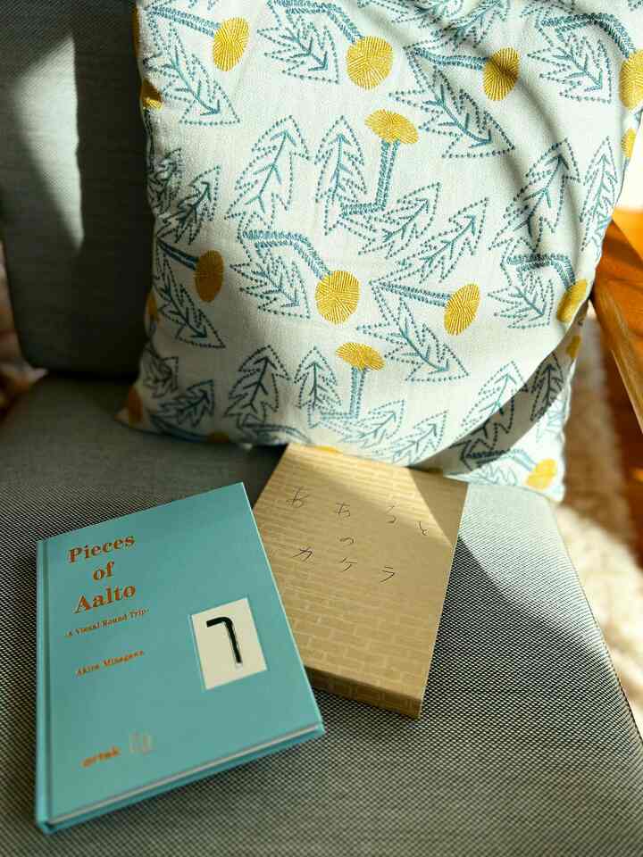 Cozy Scandinavian space featuring a gray fabric sofa with a yellow floral patterned cushion and two books bathed in warm sunlight