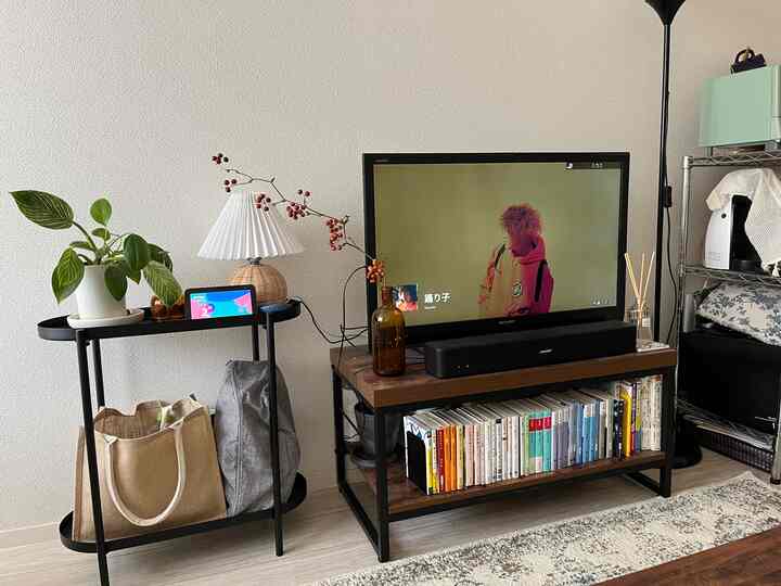 白い壁とブラウンの家具が調和したモダンで自然な雰囲気のリビング、テレビ台とサイドテーブルが配置された印象的な空間