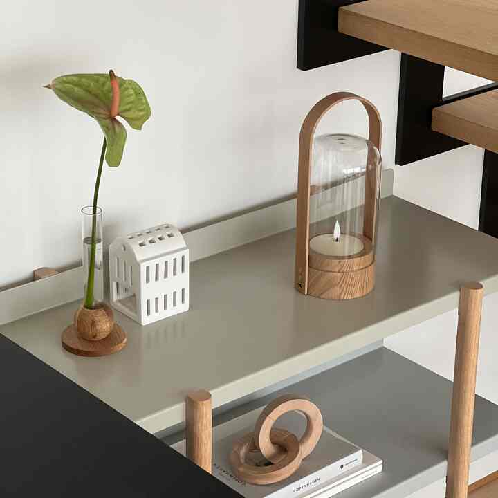 ナチュラルカラーと木目調の棚コーナー、一輪の花とキャンドルが配置されたミニマルな雰囲気のインテリア