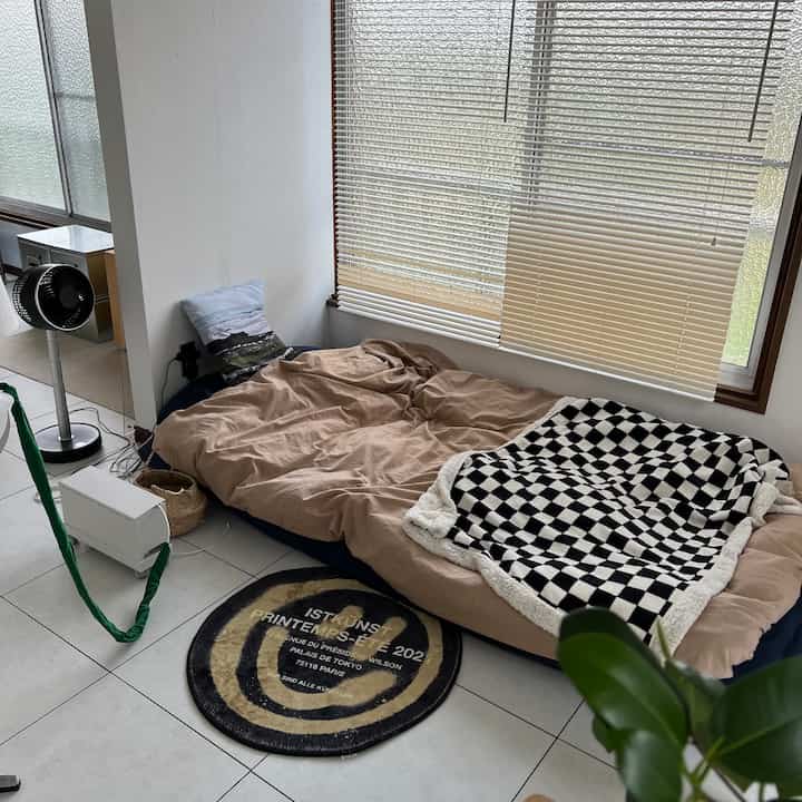 Beige floor bed placed in a small bedroom space by the window with natural lighting