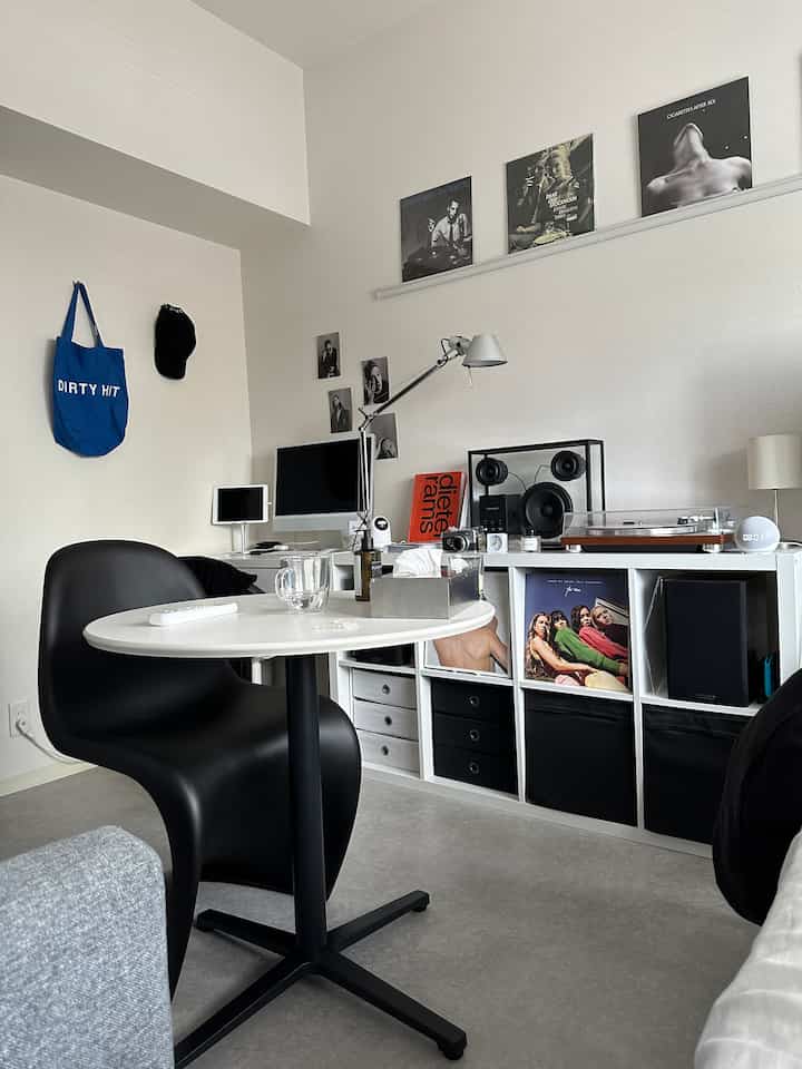 ホワイトとブラックのミニマルなホームオフィス兼リビング、コンピュータとオーディオシステムが配置された整った空間