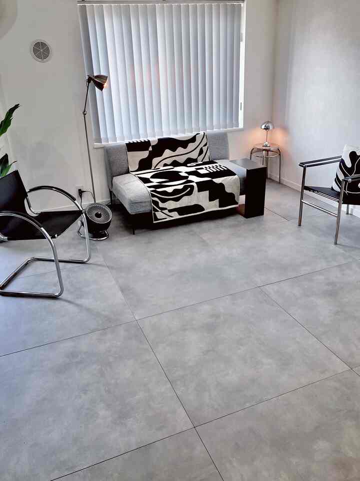 Monotone mid-century modern living room with gray sofa, armchairs, and vertical blinds in a simple layout