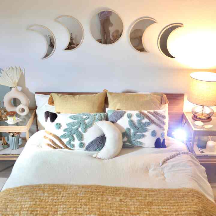 Yellow and mint toned bedroom featuring bed with cushions, nightstands, and moon-shaped wall lights creating a cozy atmosphere