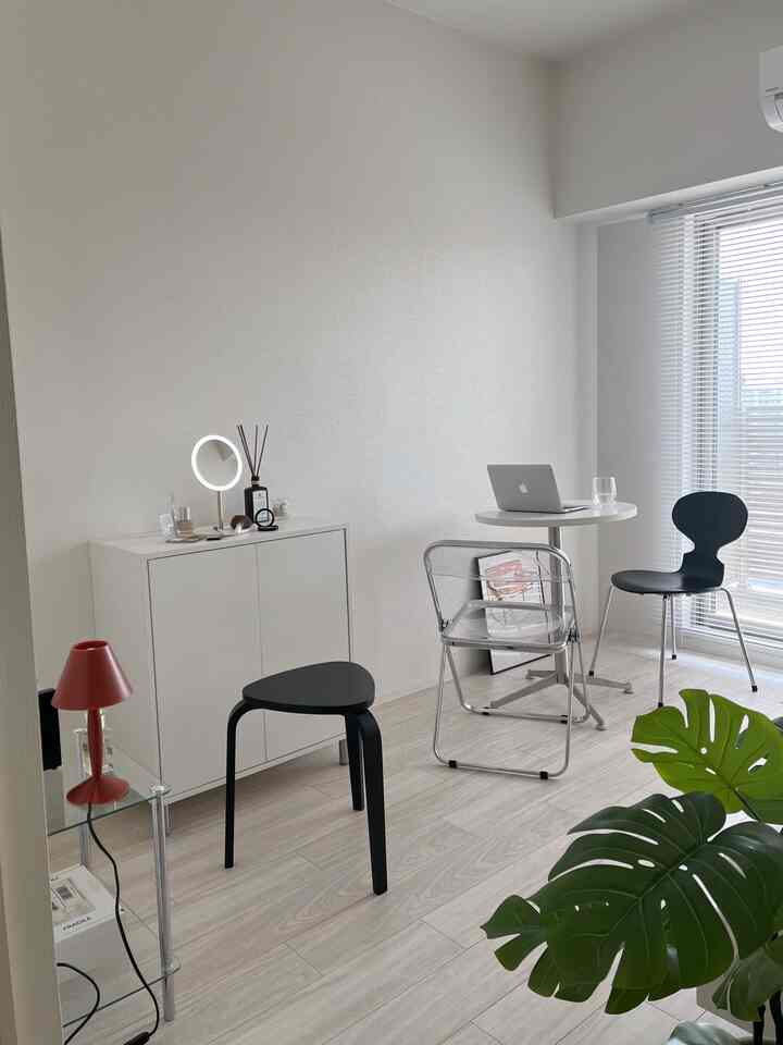 White and black toned living room featuring stool, transparent chair, and small table lamp with a clean modern atmosphere