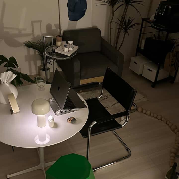 ナチュラルカラーと白を基調としたホームオフィス兼リビング、アームチェアとオフィスチェアが配置された落ち着いた空間