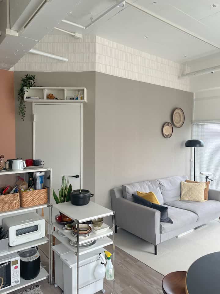 ナチュラルな色調のリビング、グレーのソファとキッチンワゴン、クッションや壁飾りが印象的な雰囲気のあるインテリア