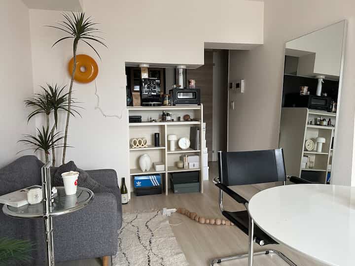 Natural-toned living room featuring a white round table, black armchair, and grey sofa in a modern interior setup