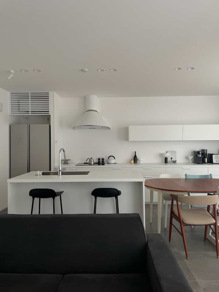 白と黒の調和が美しいモダンなキッチンとダイニング、機能的なソファが配置された清潔感のある空間