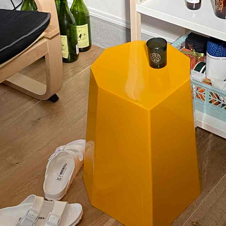 木目調の床に配置された黄色のモダンなスツールと白いビルケンシュトックサンダルがある清潔感のあるバルコニー空間