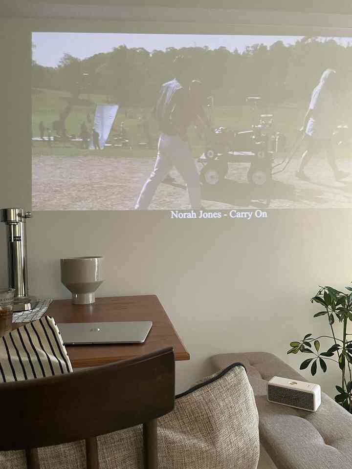 ナチュラルな色調のダイニングルーム、木製ダイニングテーブルとベンチ、プロジェクター画面が配置された雰囲気のある空間