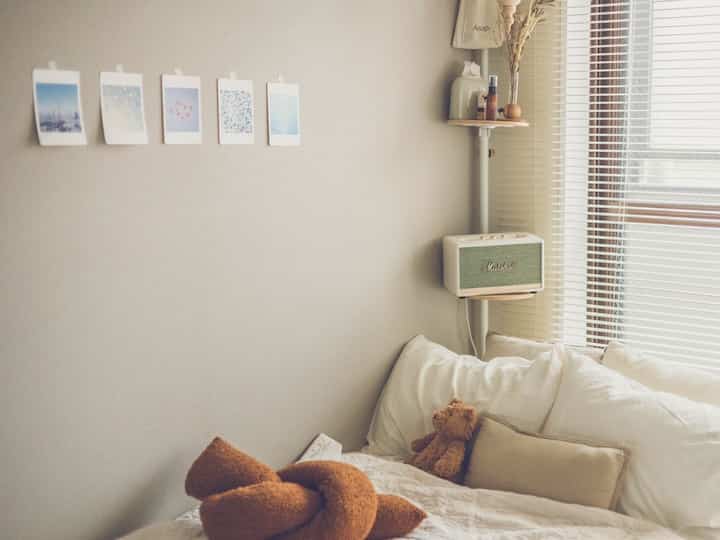 White and beige toned bedroom featuring cushions and a teddy bear creating a cozy atmosphere