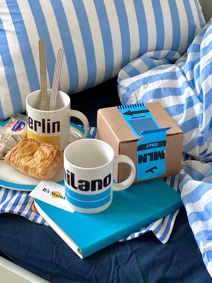 Blue and white striped bedding bedroom featuring two mugs and pastry arranged for cozy morning breakfast