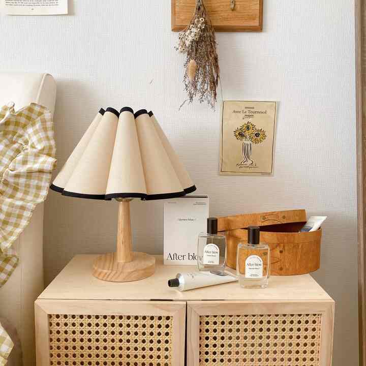 ナチュラルカラーと木目調の寝室、ナイトテーブルの上にテーブルランプや小物が配置された雰囲気のあるインテリア