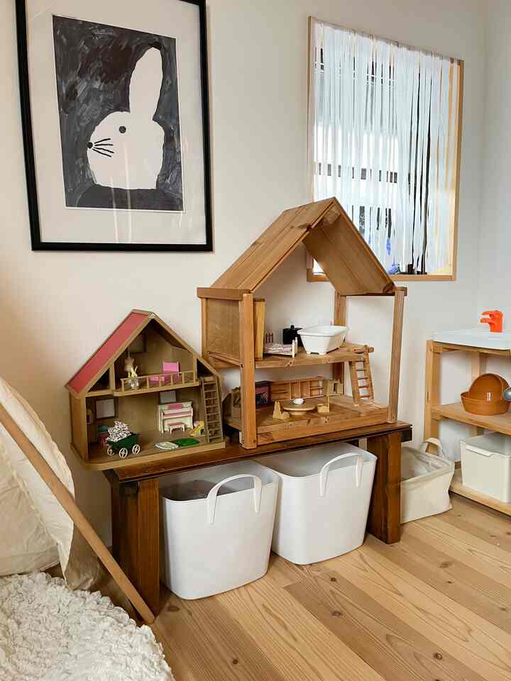 木目調と白を基調とした子供部屋、玩具収納用のソフトバスケットと木製ドールハウスが配置された雰囲気のあるインテリア