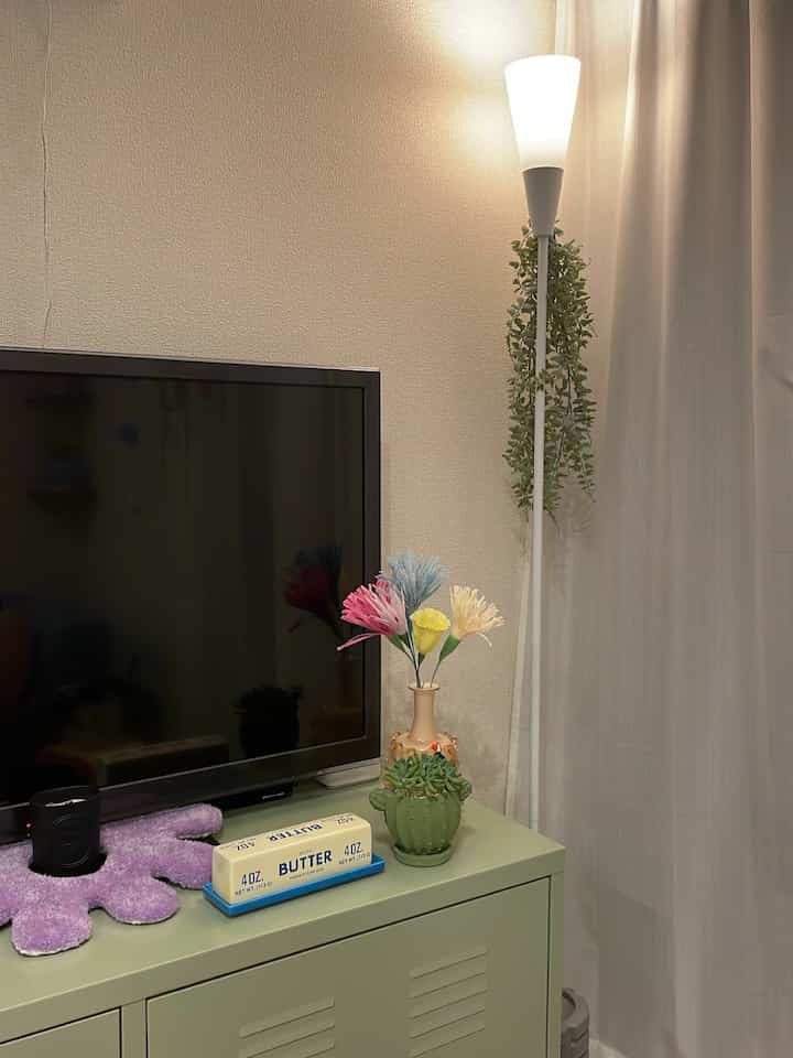 暖かい色調のリビング、ミントグリーンの鉄製キャビネットと間接照明が配置された雰囲気ある空間