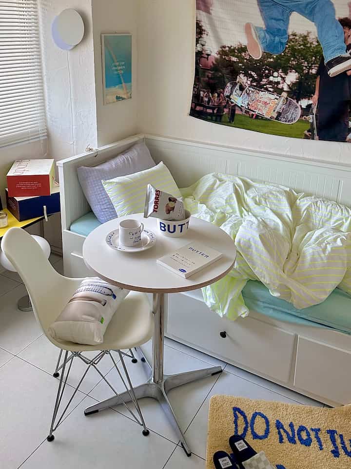 White-tone small bedroom featuring a round table and sofa bed arranged neatly in a natural modern style