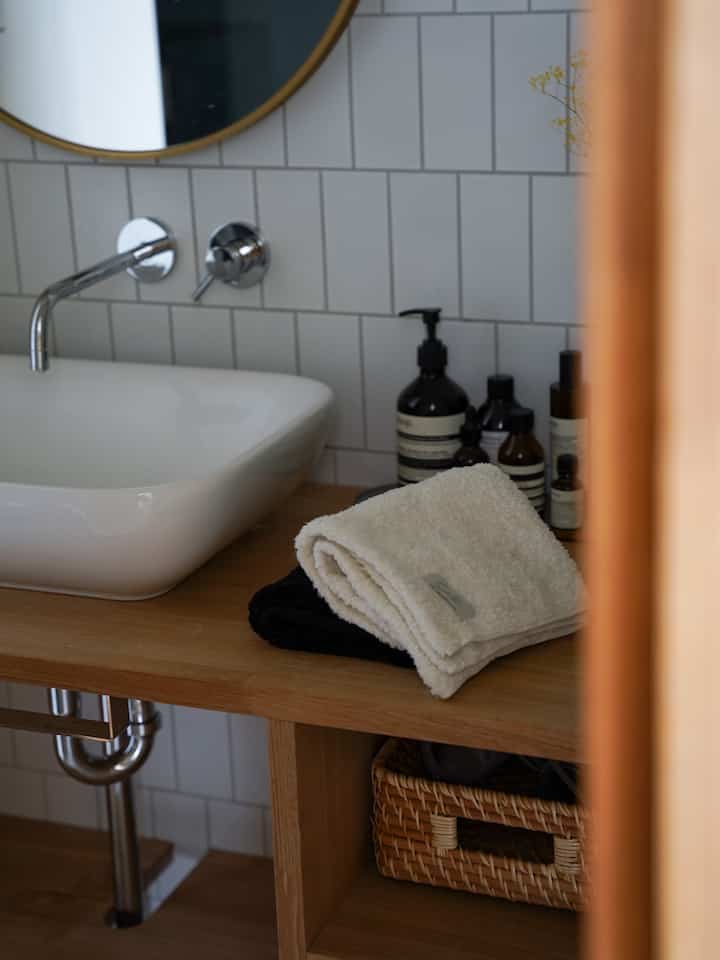 白と黒のタオルが置かれた木目調のバスルーム洗面台、清潔感と温かみのあるインテリア