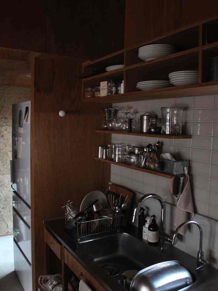 ナチュラルな木目調のキッチンスペース、棚に皿やグラスが整然と並び、シンクと収納アイデアが際立つ落ち着いた雰囲気のインテリア