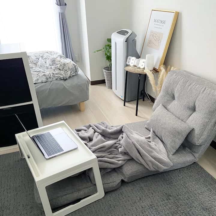 明るいグレーとホワイトのワンルーム空間、ソファベッドとトレイテーブルが配置された落ち着いた雰囲気のインテリア