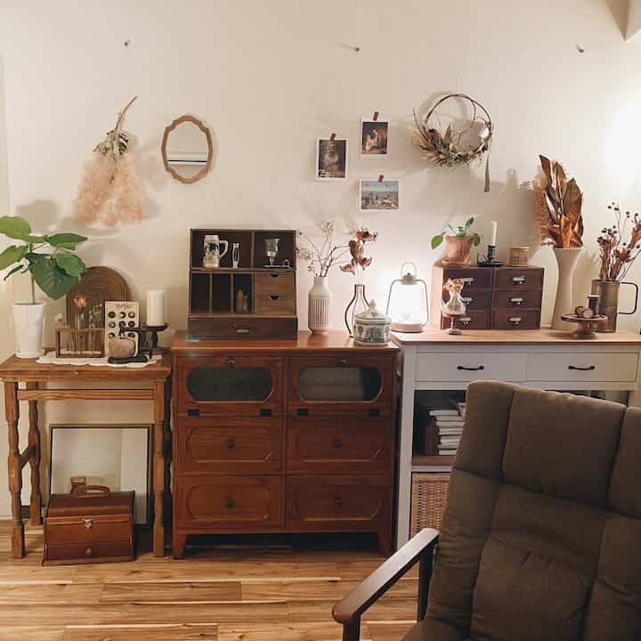 ナチュラルカラーのリビング、レトロな収納家具とアンティーク小物が配置された雰囲気のある空間