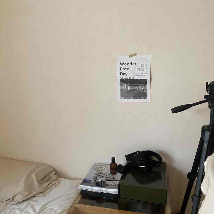 Beige-toned bedroom with wooden side table, simple space featuring bed and camera beside the bed