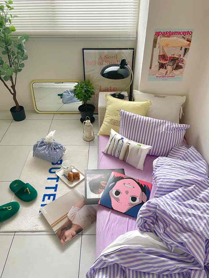 ナチュラルトーンの寝室、パープルのストライプ寝具とポスター、植物が配置された雰囲気のあるインテリア