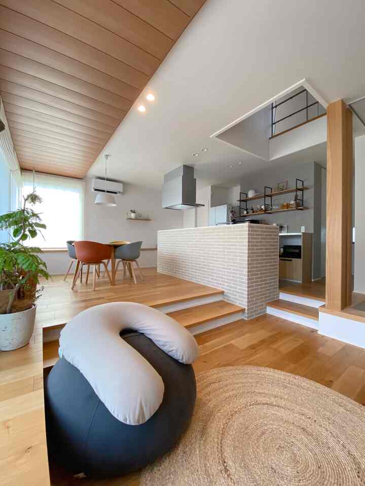 ナチュラルな木目調と白い壁のワンルーム、ビーズクッションとダイニングテーブルが配置された開放感のある清潔な空間