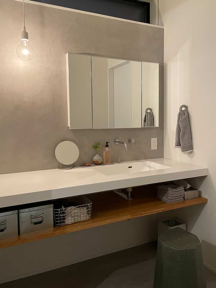 Modern bathroom with gray Mortex wall, a pendant light, and a white washbasin countertop
