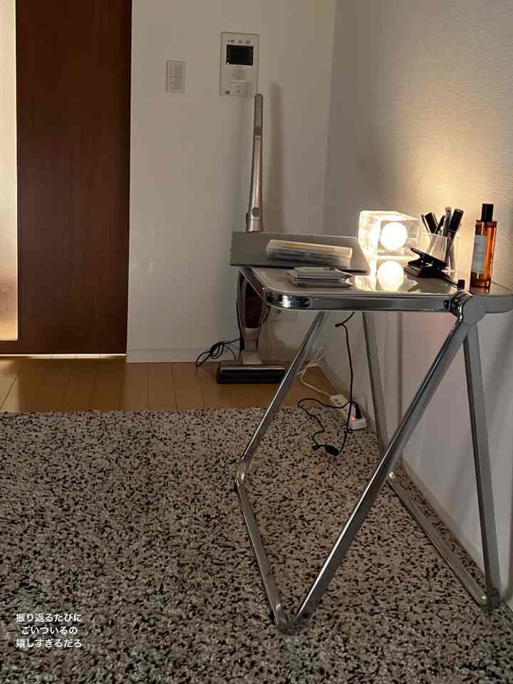 白い壁と茶色の床が調和するコンパクトな空間、シルバーのメタルテーブルと照明が配されたモダンなホームオフィス