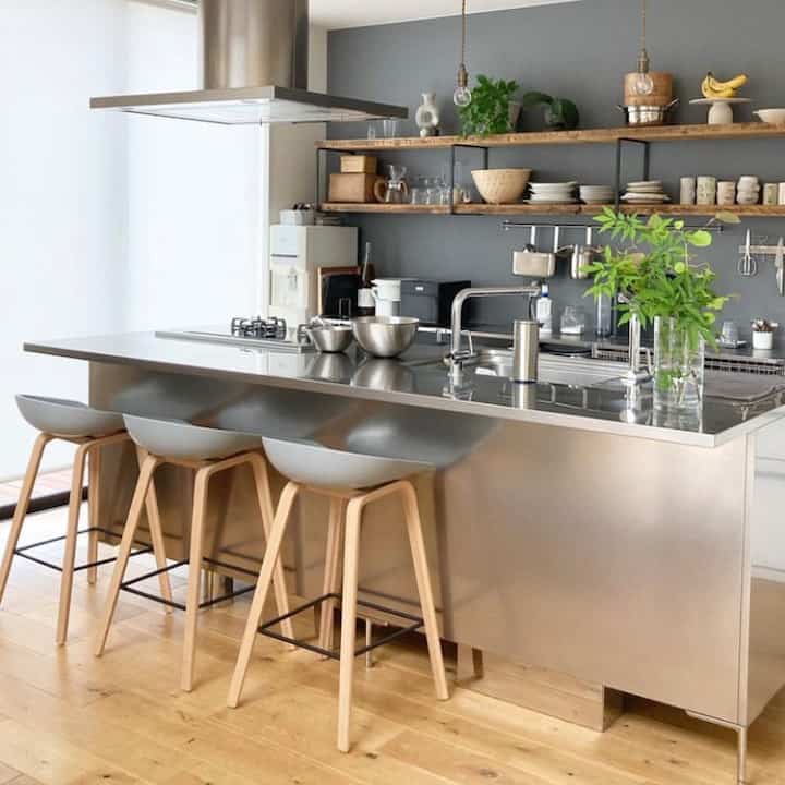 ナチュラルカラーのキッチン、ステンレス製のアイランドとカウンタースツールが配置されたシンプルモダンなインテリア