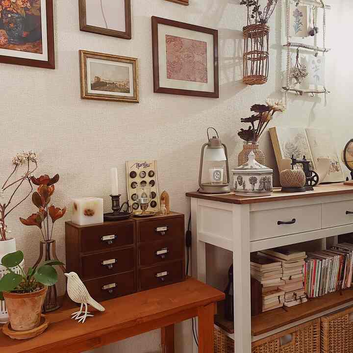 ベージュの壁とナチュラルウッドの家具、額縁や多様なインテリアが配された温かみのあるリビング